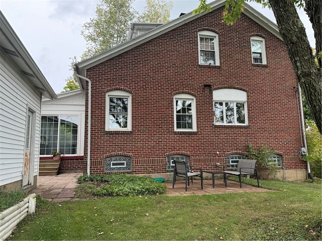 rear view of house featuring a lawn and a patio