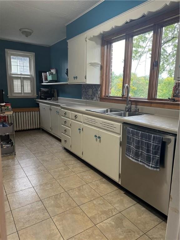 kitchen with a wealth of natural light, sink, dishwasher, radiator heating unit, and white cabinetry