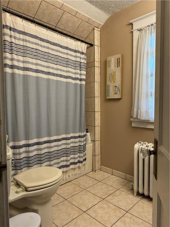 bathroom featuring shower / bath combination with curtain, a textured ceiling, tile patterned flooring, radiator heating unit, and toilet