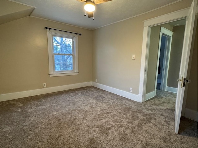 carpeted empty room featuring ceiling fan, ornamental molding, and vaulted ceiling