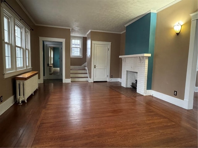 unfurnished living room with dark wood-type flooring, radiator, ornamental molding, a textured ceiling, and a fireplace