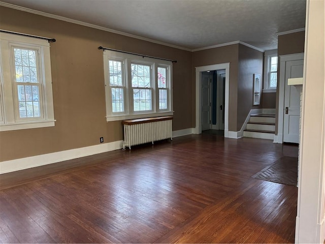 spare room featuring radiator heating unit, dark hardwood / wood-style floors, crown molding, and a healthy amount of sunlight