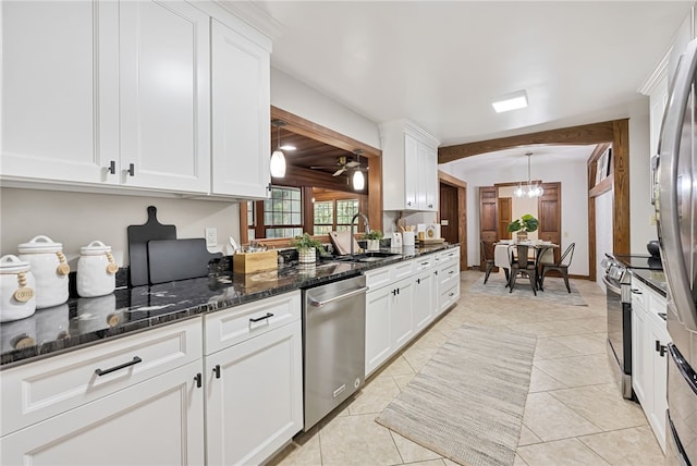 kitchen with light tile patterned floors, decorative light fixtures, white cabinetry, appliances with stainless steel finishes, and ceiling fan with notable chandelier