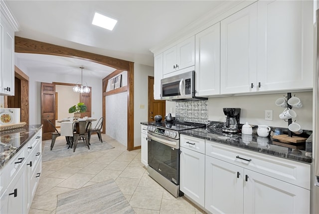 kitchen with pendant lighting, dark stone counters, white cabinetry, an inviting chandelier, and appliances with stainless steel finishes