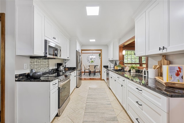 kitchen featuring dark stone counters, light tile patterned floors, and stainless steel appliances