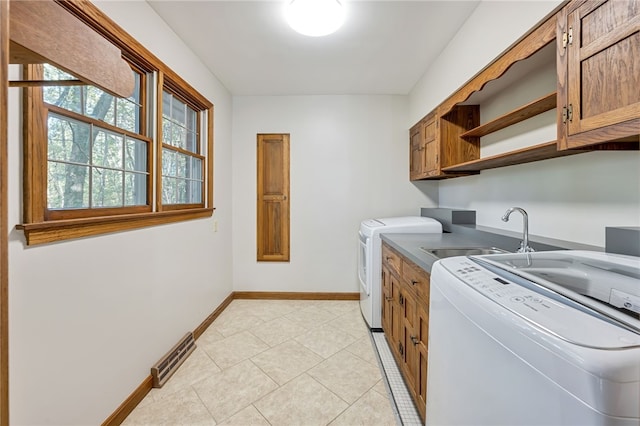 washroom with light tile patterned flooring, sink, washer and dryer, and cabinets