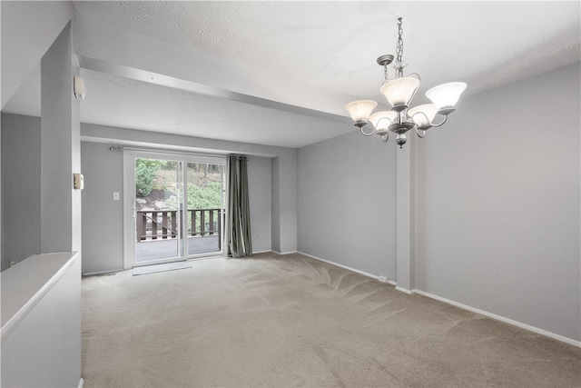 spare room featuring a textured ceiling, an inviting chandelier, and light colored carpet