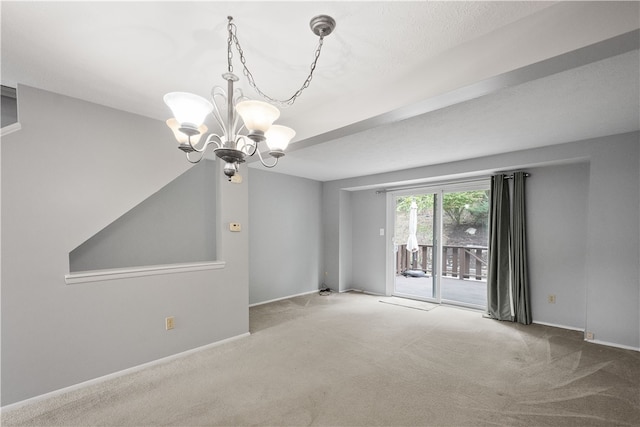 spare room featuring a chandelier and carpet floors