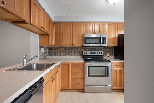 kitchen featuring decorative backsplash, light hardwood / wood-style floors, sink, and stainless steel appliances