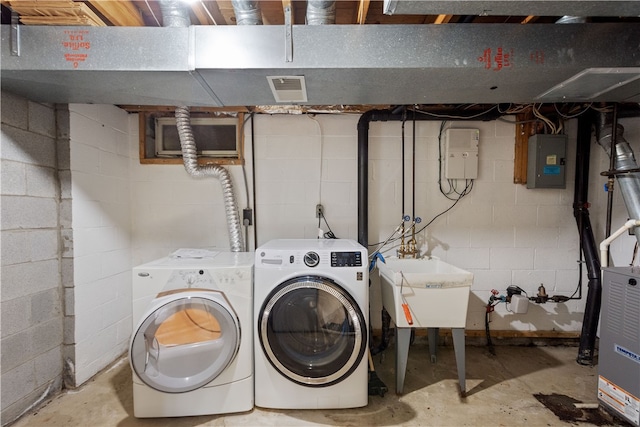 washroom featuring separate washer and dryer, electric panel, and sink