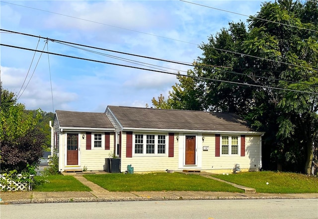 ranch-style house with a front yard and central air condition unit