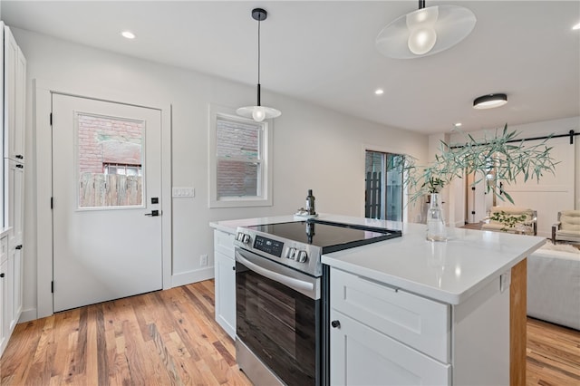 kitchen featuring white cabinetry, electric stove, light hardwood / wood-style floors, decorative light fixtures, and a center island