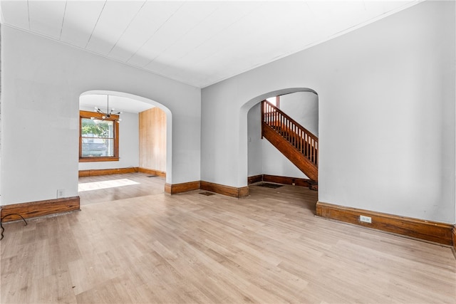 spare room with light hardwood / wood-style flooring and an inviting chandelier