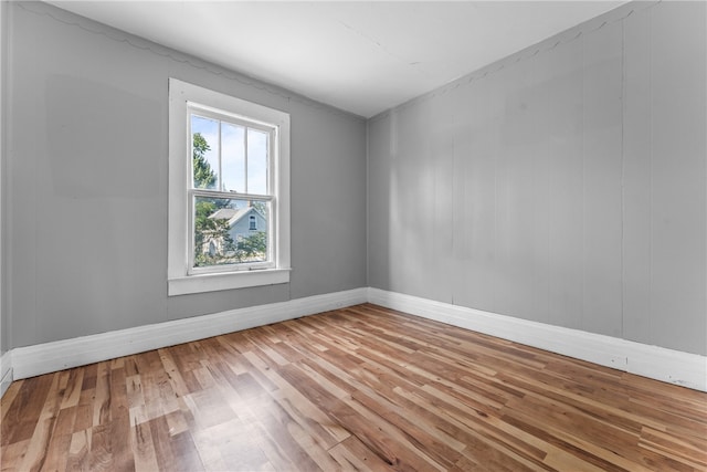 empty room featuring light hardwood / wood-style flooring and wooden walls