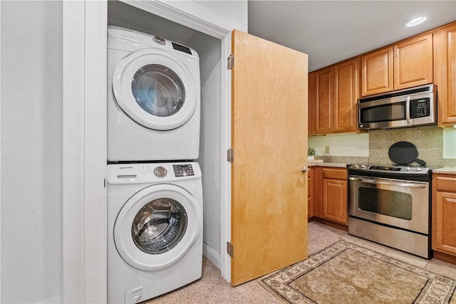 laundry area with light tile patterned floors and stacked washer and dryer