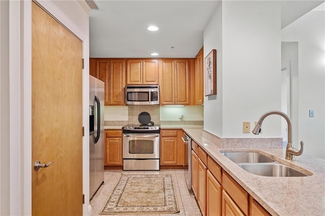 kitchen featuring light stone countertops, appliances with stainless steel finishes, light tile patterned flooring, and sink