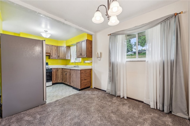 kitchen featuring stainless steel fridge, pendant lighting, white stove, an inviting chandelier, and sink