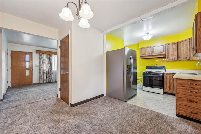 kitchen featuring stainless steel fridge, sink, decorative light fixtures, a chandelier, and white range with gas cooktop