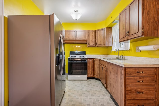 kitchen featuring sink, white range with gas cooktop, and stainless steel fridge