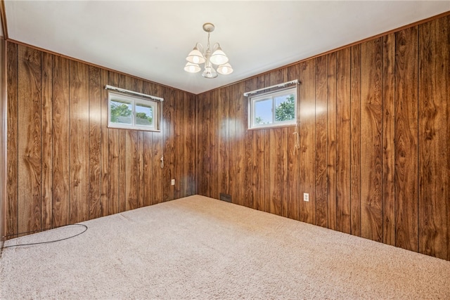 unfurnished room with carpet, wooden walls, and an inviting chandelier