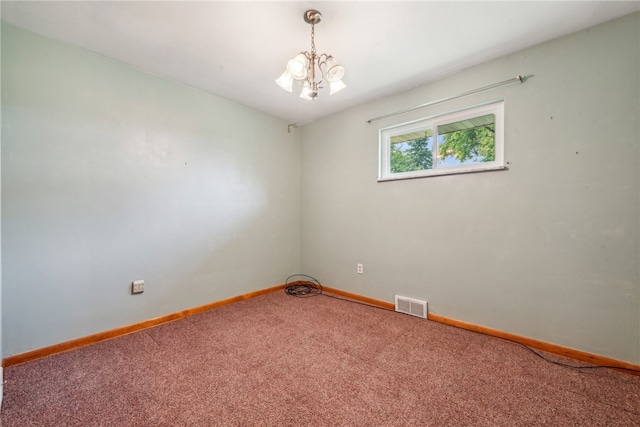 carpeted spare room featuring a chandelier