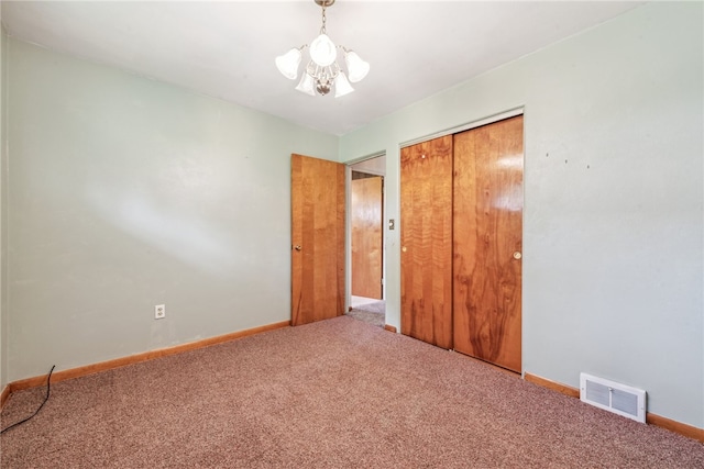 unfurnished bedroom with a closet, a chandelier, and carpet flooring