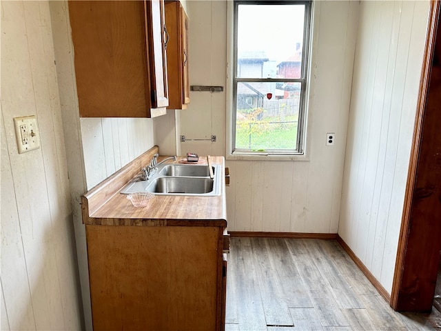 kitchen featuring wood walls, light hardwood / wood-style floors, and sink