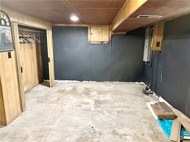 basement with wood walls and electric panel