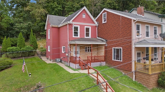 rear view of property with a lawn and cooling unit