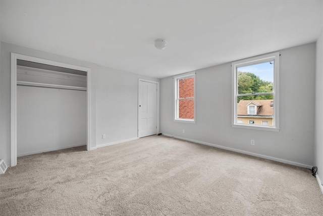 unfurnished bedroom with light carpet and a closet