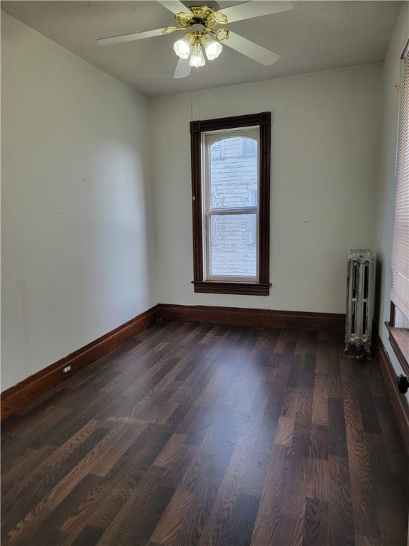 unfurnished room with radiator, ceiling fan, and dark wood-type flooring