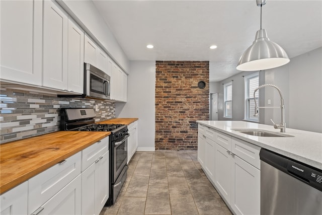 kitchen featuring white cabinets, appliances with stainless steel finishes, sink, and decorative light fixtures