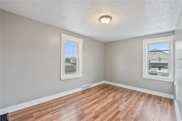 spare room with a textured ceiling and hardwood / wood-style flooring