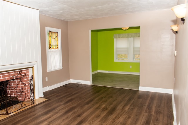 unfurnished living room with a textured ceiling, dark hardwood / wood-style flooring, and a brick fireplace