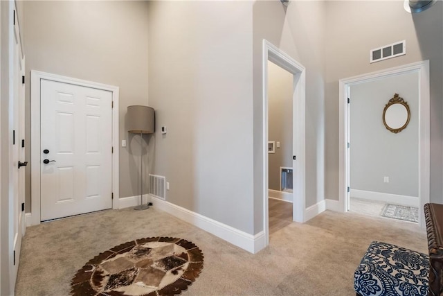 carpeted foyer with a towering ceiling