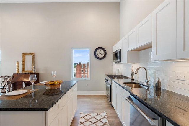 kitchen with dark stone countertops, appliances with stainless steel finishes, sink, and white cabinets