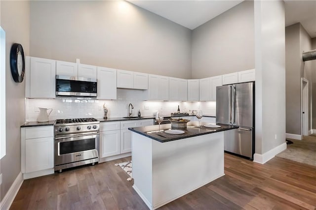 kitchen featuring stainless steel appliances, white cabinetry, a high ceiling, and dark hardwood / wood-style flooring