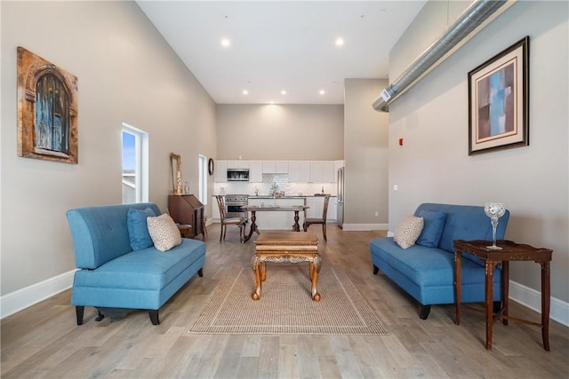 living room with a towering ceiling and light hardwood / wood-style floors