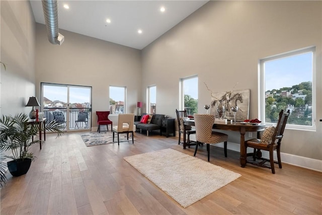 interior space featuring plenty of natural light, a towering ceiling, and light wood-type flooring