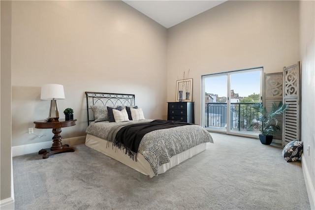 carpeted bedroom featuring access to exterior and a high ceiling