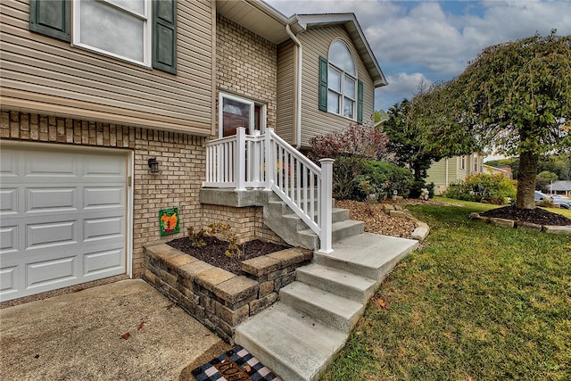 doorway to property with a garage and a yard