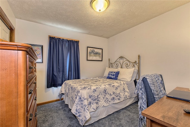 bedroom with dark colored carpet and a textured ceiling