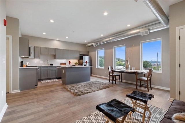 kitchen with sink, gray cabinetry, stainless steel appliances, light hardwood / wood-style floors, and a kitchen island