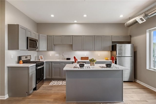 kitchen with gray cabinets, appliances with stainless steel finishes, a center island, and sink