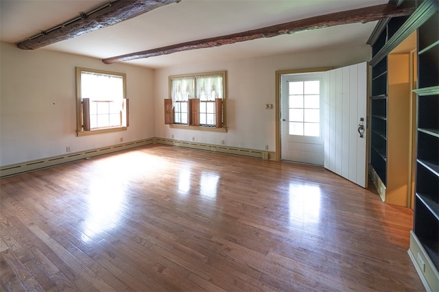 empty room featuring a baseboard heating unit, hardwood / wood-style flooring, and plenty of natural light