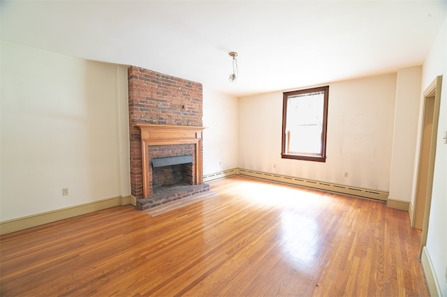 unfurnished living room with hardwood / wood-style floors, baseboard heating, and a brick fireplace