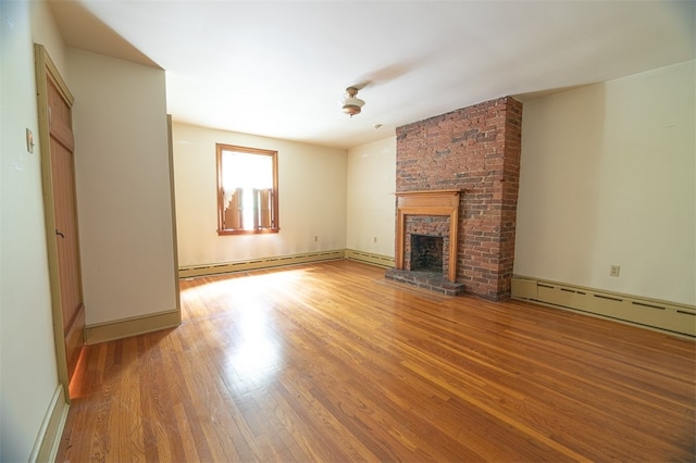 unfurnished living room with a brick fireplace, a baseboard heating unit, and wood-type flooring