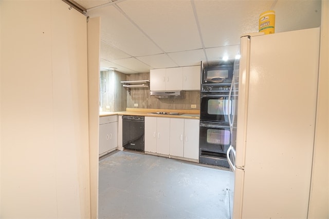 kitchen with white cabinets, backsplash, black appliances, concrete flooring, and a paneled ceiling