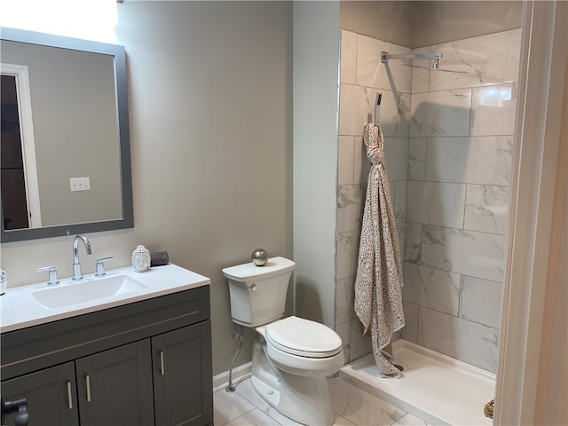 bathroom with vanity, toilet, and tiled shower