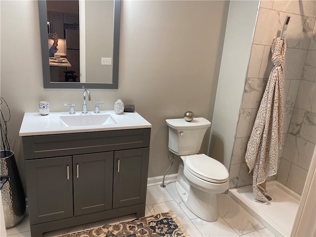 bathroom with toilet, vanity, tile patterned floors, and tiled shower